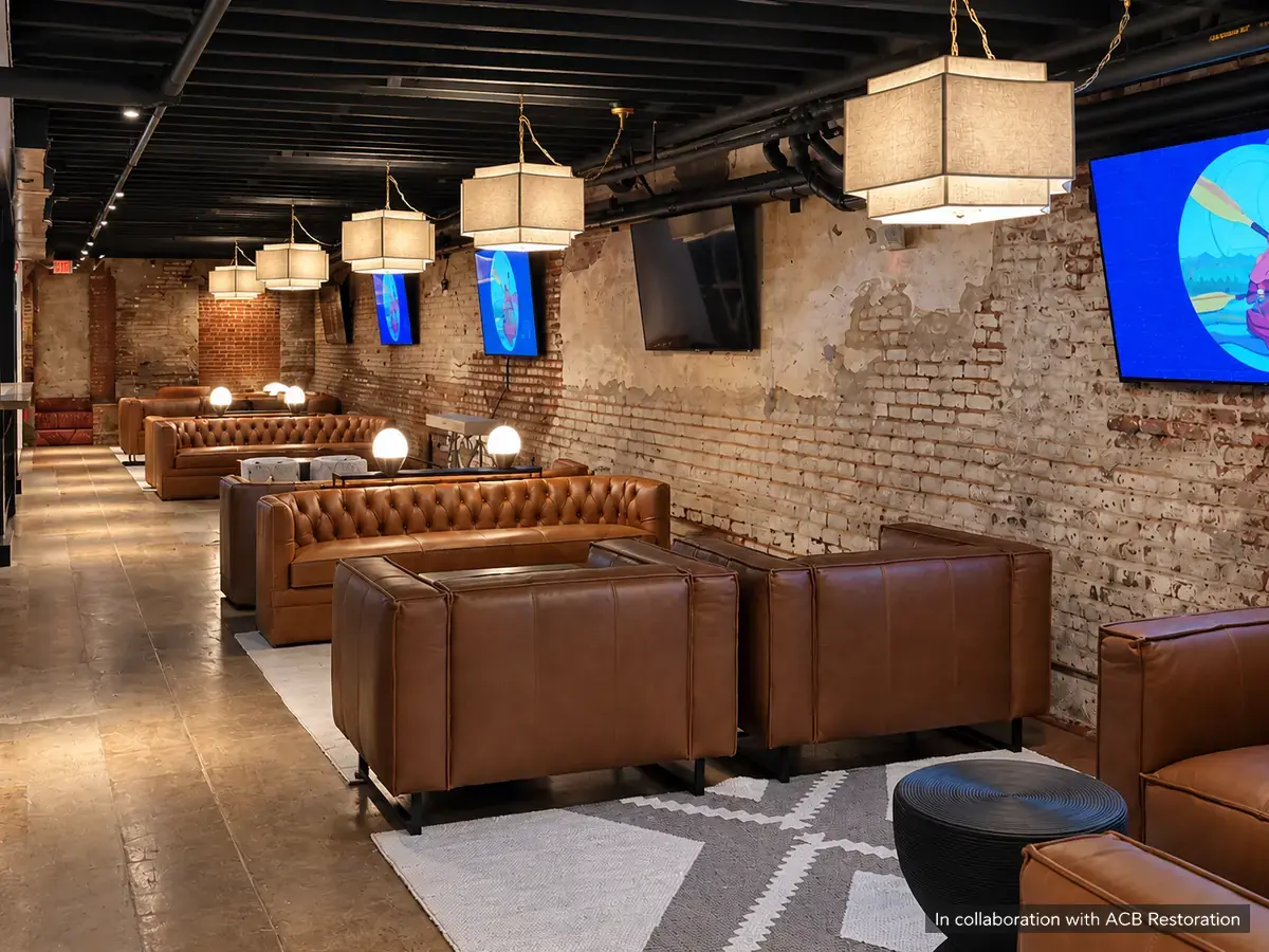 Restaurant lounge with leather seating, exposed brick walls and warm pendant lighting. In collaboration with ACB Restoration.
